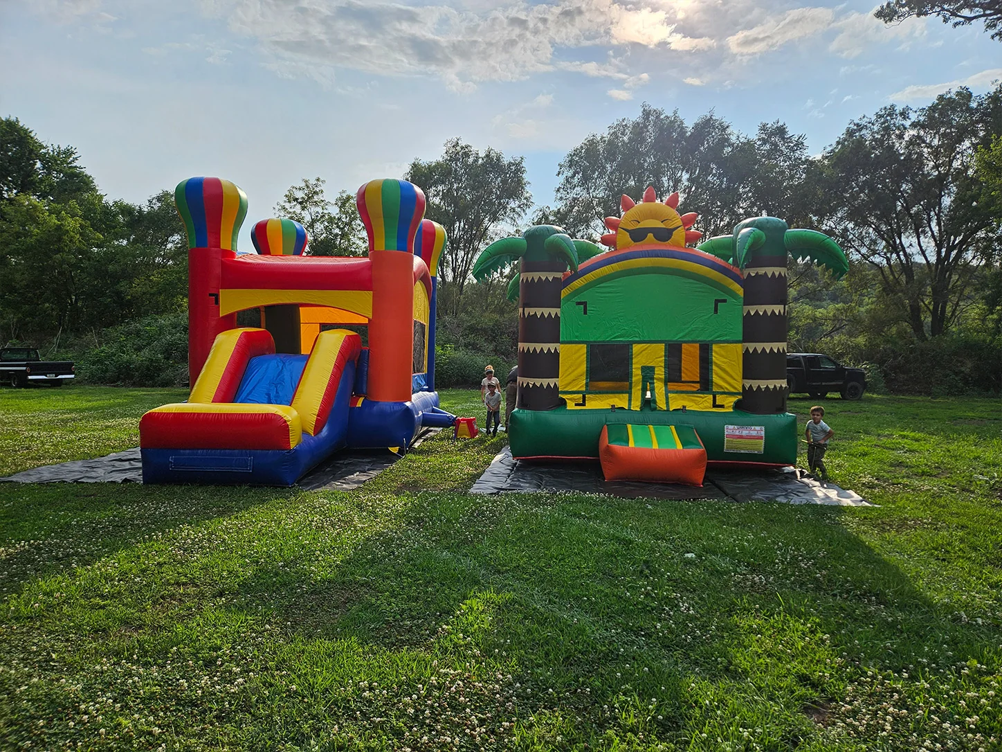 Two colorful bounce houses set up outdoors for a family celebration