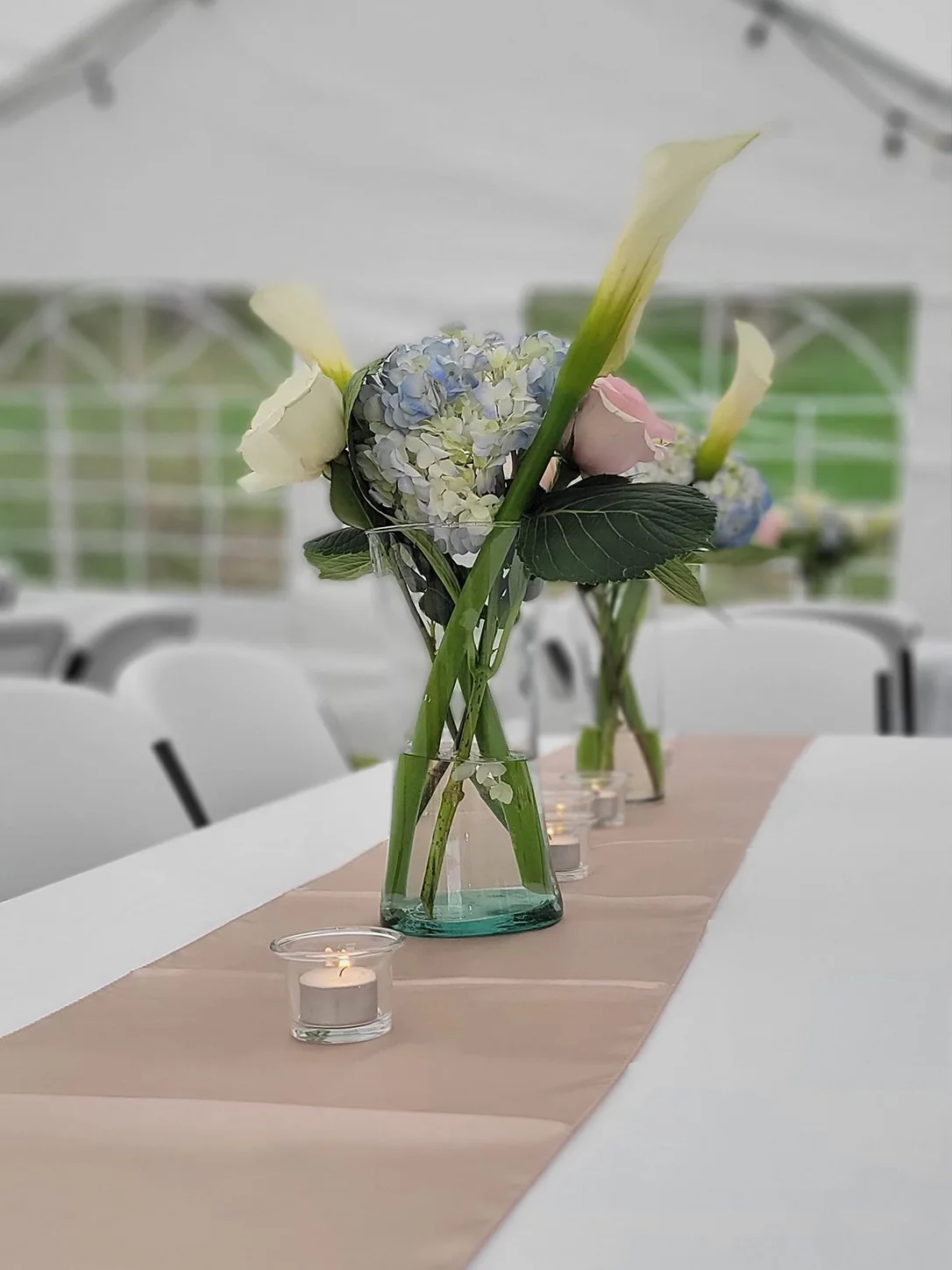 Pastel floral centerpiece with candles on a dressed event table