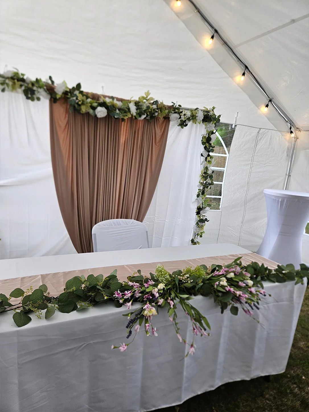 Decorated event backdrop, floral table garland, and cocktail table