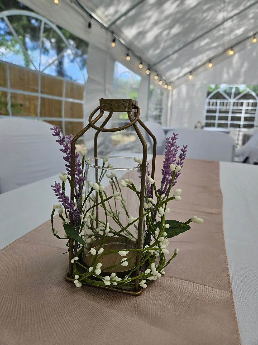 Bronze lantern centerpiece decorated with lavender and greenery